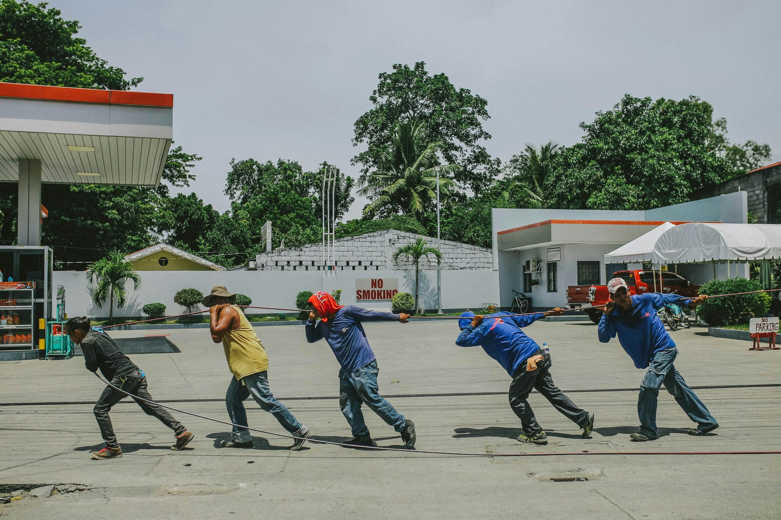 A group of workers installing cables at a gas station during daytime.